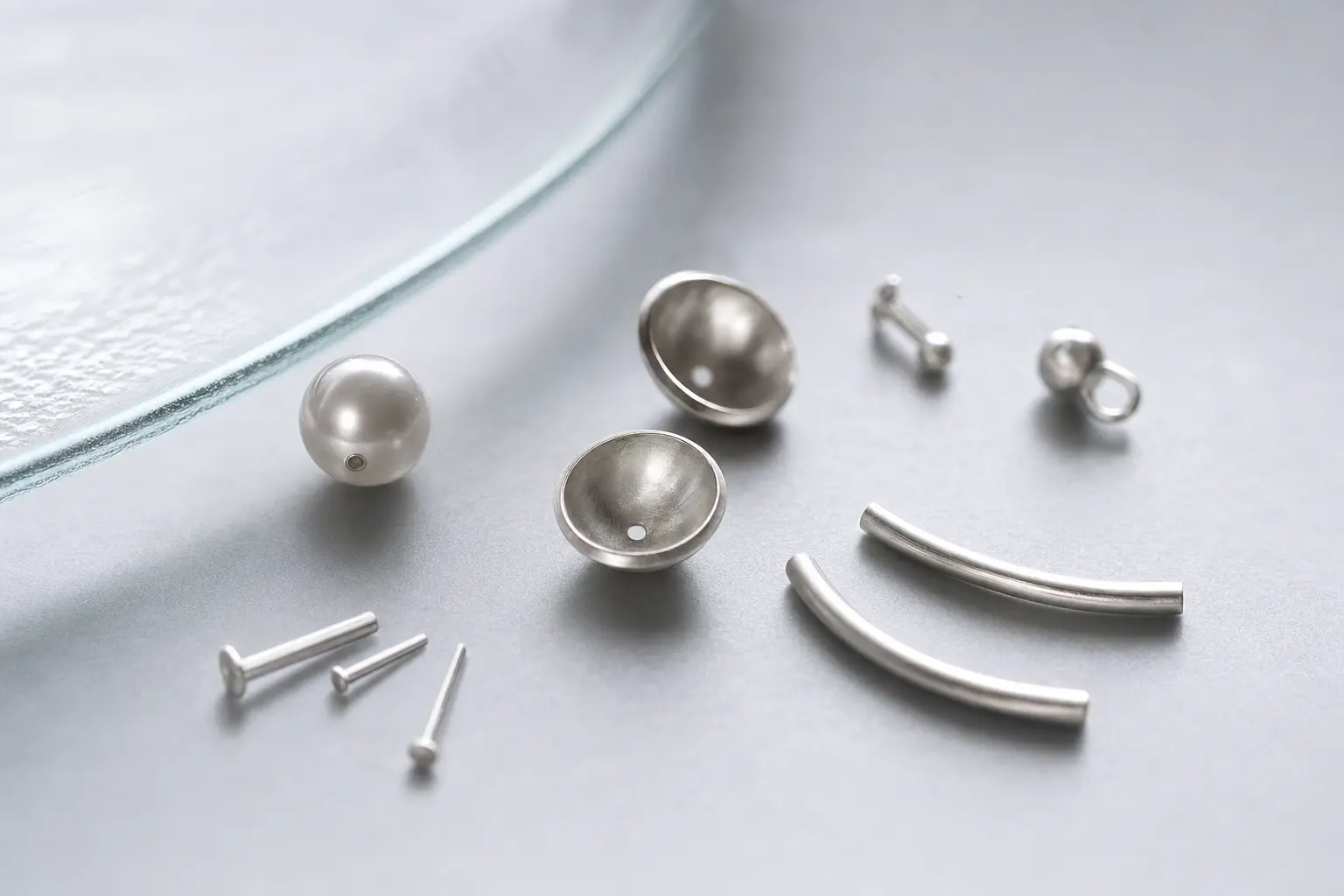 Pearl-like beads and tiny silver posts arranged on frosted glass