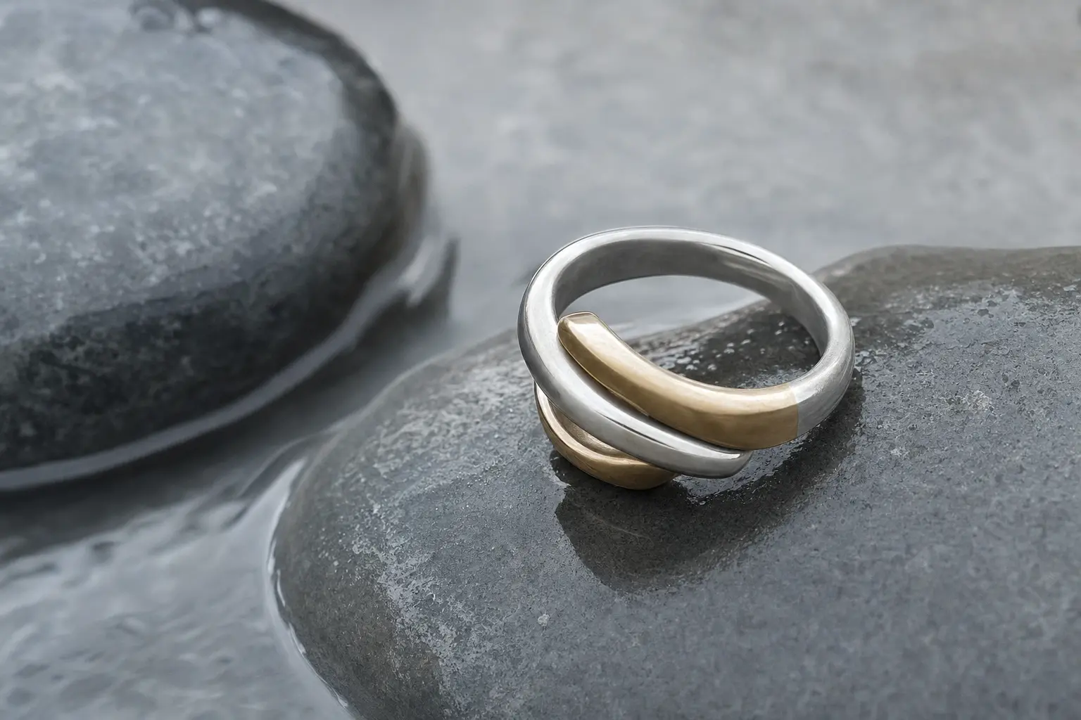 Two-tone silver and champagne brass ring sample on gray stones