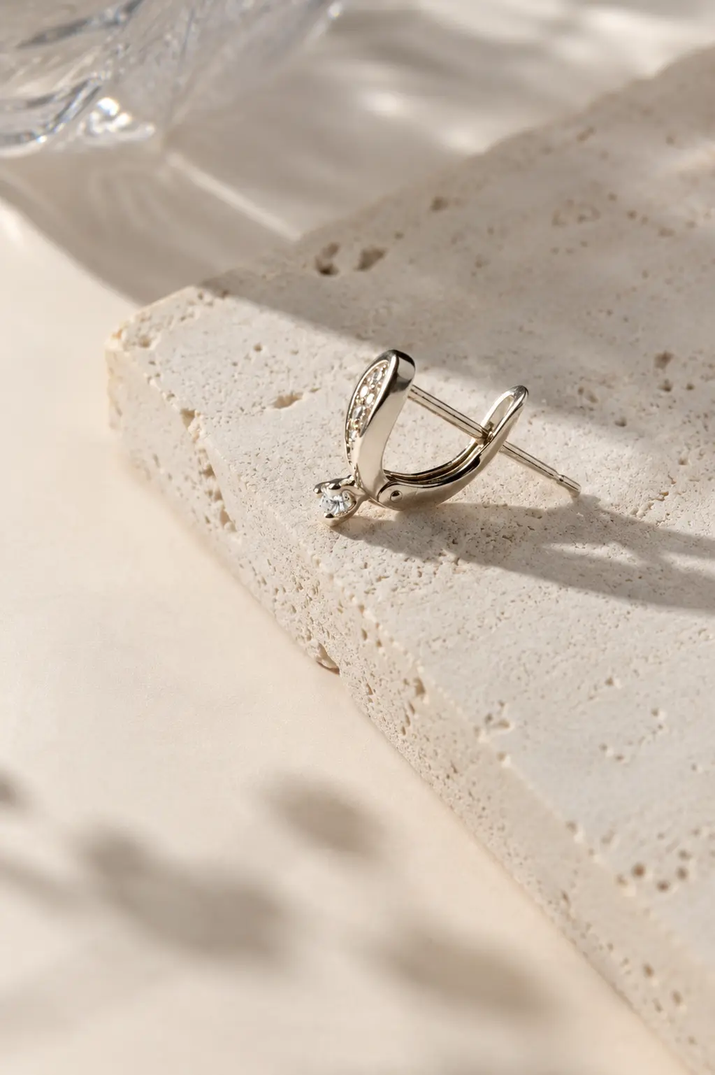 Silver hoop earring photographed on pale textured stone