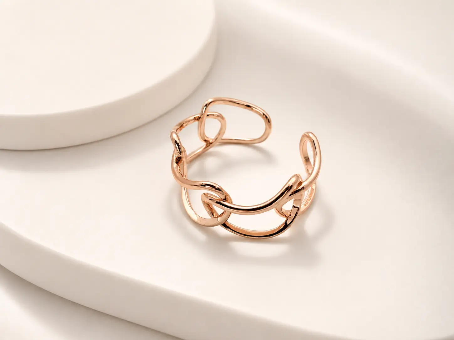 Rose-gold cuff bracelet photographed on a soft cream surface